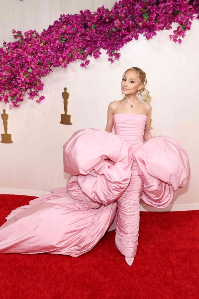 Ariana Grande arrived at the 2024 Oscars channeling her 'Wicked' character in a baby pink Giambattista Valli column dress and matching cape.