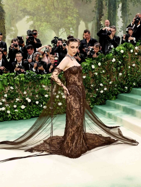 Emma Chamberlain has arrived at the 2024 Met Gala. She offers up an eerie gothic take on the theme, "The Garden of Time", in a brown lace custom Jean Paul Gaultier bodysuit. See her full girly goth look here.