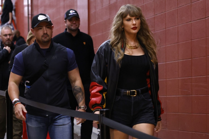 Taylor Swift arrives at boyfriend Travis Kelce's football game on Friday, November 29. She wore black skinny jeans tucked into her ankle boots and a red Louis Vuitton quarter-zip sweater.