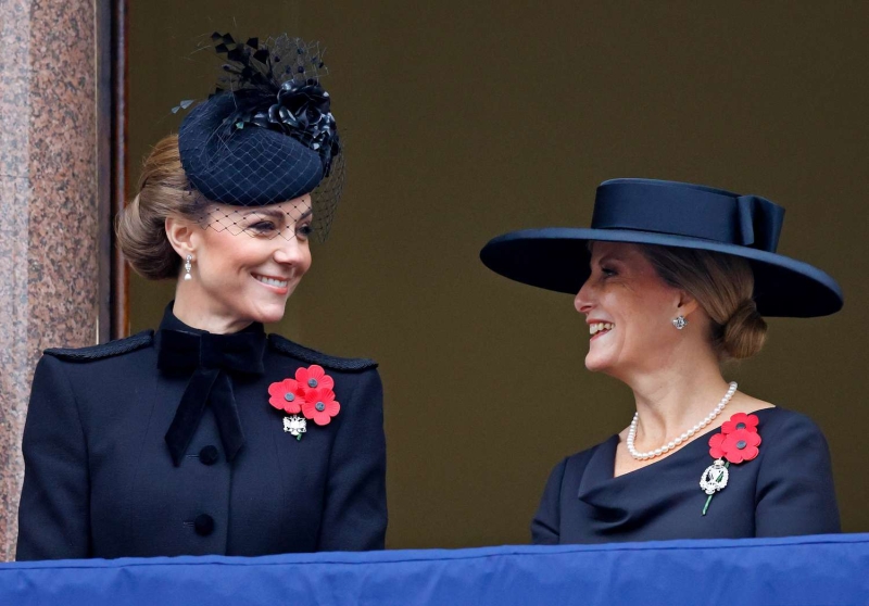 Kate Middleton arrived at her annual Christmas Carol concert wearing a floor length red pea coat that feature a large, black velvet bow at the neckline. She accessorized with velvet black boots.