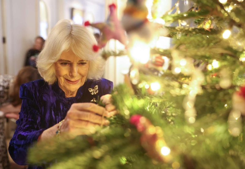 Queen Camilla sported a blue velvet dress paired with her moth brooch for a Christmas tree decorating event at Clarence House.